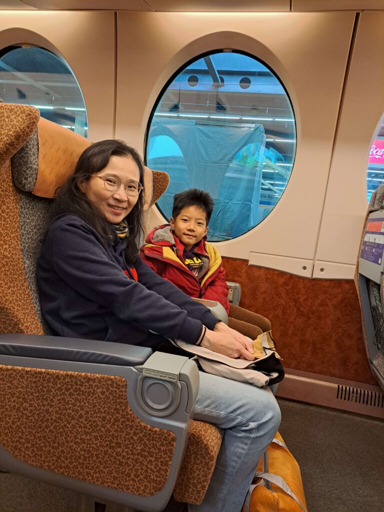 南海電鐵 Rapi:t 特急電車內,老婆與兒子坐在經典圓形車窗旁放鬆微笑